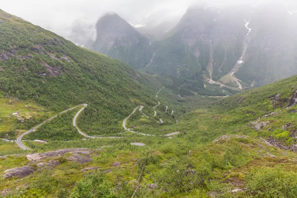 Zakřivená a osamělá cesta mezi norskými horami pod zataženou oblohou, selektivní zaměření — Stock fotografie