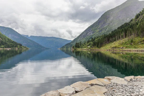 Norwegian fjord and mountains surrounded by clouds, ideal fjord reflection in clear water. selective focus.