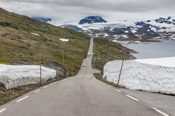 Summer road leading a mysterious gorge surrounded by snow in Norwegian mountains, selective focus — 스톡 사진