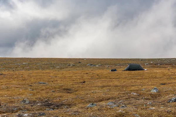 가을철에는 구름 이 빽빽 하게 끼어 있는 극적 인 하늘 아래 천막 이 우뚝 솟아 있습니다. 산속 의외로운 천막. — 스톡 사진
