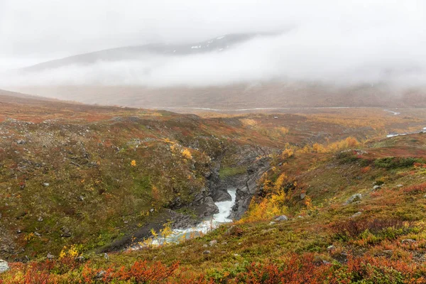 Dağın yamacında duran küçük evleri ve vadiyi ve içinden akan nehri görürüz. Sonbahar, Sarek. — Stok fotoğraf