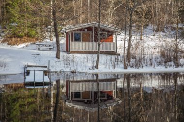 İsveç 'te kış manzarası. Gölde eriyen karlar. Sudaki küçük bir evin yansıması. seçici odak