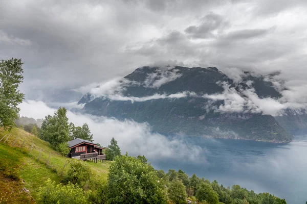 Norveç fiyortlarının dağlarında turkuaz suyla tipik bir ev.