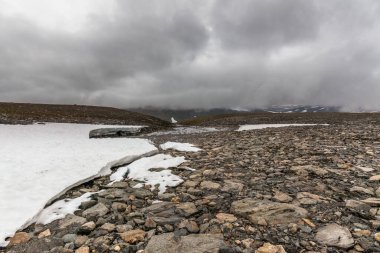 İsveç Laponya 'daki Sarek ulusal parkının güzel vahşi doğası. Karlı dağ zirveleri, nehir ve göl, huş ağacı ve çam ağaçları ormanı. Fırtınalı havada sonbahar renkleri. seçici odak