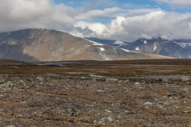 İsveç Laponya 'daki Sarek ulusal parkının güzel vahşi doğası. Karlı dağ zirveleri, nehir ve göl, huş ağacı ve çam ağaçları ormanı. Fırtınalı havada sonbahar renkleri. seçici odak