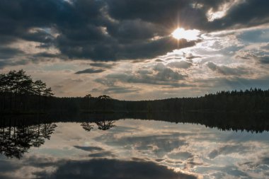 Gölün üzerinde gün batımı. Göl gün batımında bulutları yansıtır. İsveç