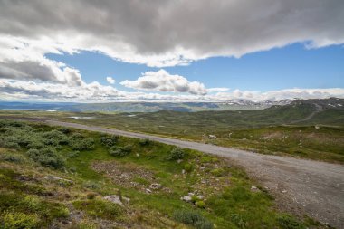 The road leading a mysterious valley surrounded by clouds in Norwegian mountains.