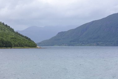 Norveç 'te gizemli bir fiyort. Dağlar ve sis, suyun üzerinde tek renkli güzel bir renkle süzülüyor. seçici odak