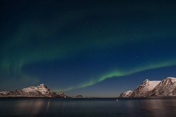 aurora borealis. Green northern lights. Starry sky with polar lights. winter landscape with aurora, sea with sky reflection and snowy mountains.