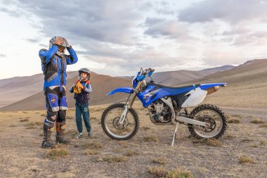Altaj, Moğolistan - 11 Haziran 2017: Motosiklet kasklı bir çocuk bir motosikletliye hayranlıkla bakıyor.