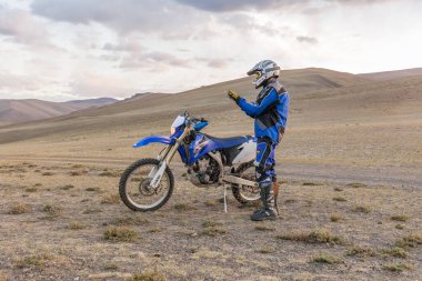Altaj, Moğolistan - 11 Haziran 2017: Moğolistan bozkırlarında motosiklet süren kasklı motosikletli gezgin.