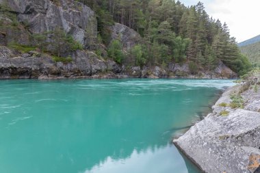 Norveç 'in doğası. Berrak suyu olan bir dağ nehri. Resimli şelalesi olan kayalık bir yamaç. Norveç 'te yürüyüş. İskandinav doğası. Yaya köprüsü olan bir dağ nehri. Norveç 'in şiddetli doğası