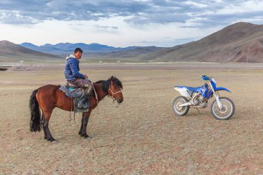 Altai, Moğolistan - 14 Haziran 2017: Moğol binicisi motosikletin yanında durdu ve turistlere baktı