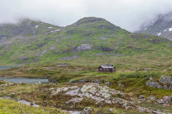 湖畔や遠くの山々に立つノルウェーの伝統的な木造住宅 — ストック写真