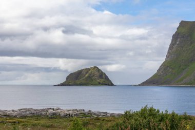 Norveç fiyortlarının bulutlu gökyüzü ve seçici odak noktalarıyla çevrili turkuaz su manzarası