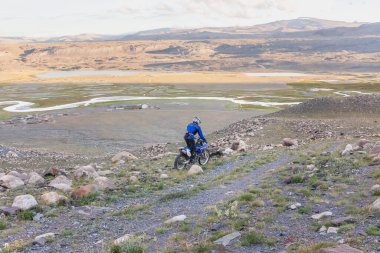 Altai, Moğolistan - 11 Haziran 2017: Moğolistan tepelerinde motosiklet süren adam.