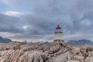 Norveç 'te beyaz deniz feneri. Uzun beyaz bir deniz feneri olan Norveç manzarası. Sert İskandinav doğasının arka planındaki deniz feneri. Norveç.