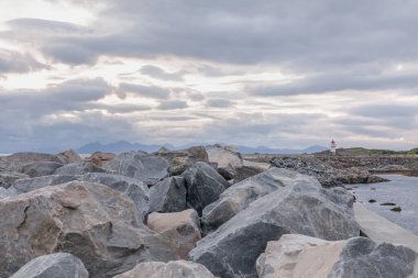 Norveç 'te kırmızı çatılı beyaz deniz feneri. Uzun beyaz bir deniz feneri olan Norveç manzarası. Sert İskandinav doğasının arka planındaki deniz feneri. Norveç.