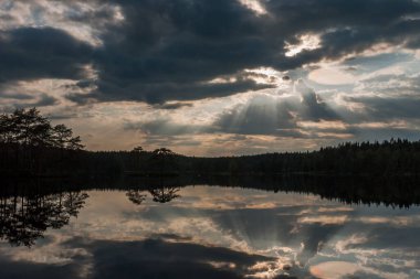Gölün üzerinde gün batımı. Göl gün batımında bulutları yansıtır. İsveç