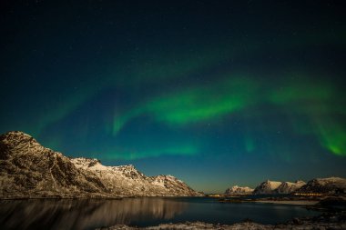 Aurora borealis, kutup ışıkları, fiyort dağlarının üzerindeki kuzey ışıkları, Avrupa 'nın kuzeyinde gökyüzünde birçok yıldız, Lofoten adaları, Norveç,.