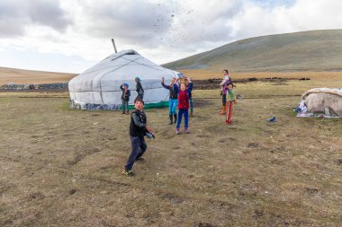 Altai, Moğolistan - 14 Haziran 2017: Moğolistan göçebelerinin küçük bir yerleşim yeri. Çocuklar dışarıda oynuyor. Yoldan geçen arabalara zemin atıyorlar.