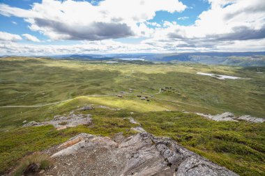 Green grass fields in Norway countryside near mountains. Cloudy foggy summer day, norwegian rural panoramic landscape. selective focus.