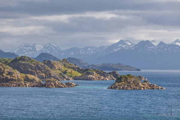 A mystical fjord in Norway with mountains and fog hanging over the water in polar day. midnight sun, selective focus