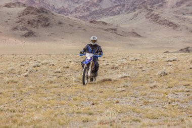 Altai, Moğolistan - 14 Haziran 2017: Moğolistan bozkırlarında motosiklet süren kasklı motosikletli gezgin.