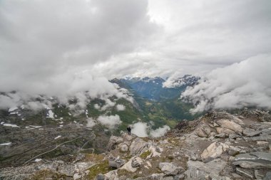Birbirine aşık çiftler dağın kenarında dururlar. Dalsnibba Dağı, Serpentine Yolu, Norveç 'ten bulutlu havada Geiranger Fiyort ve Kartal Yolu' na bakın. Bakış açısından bak.