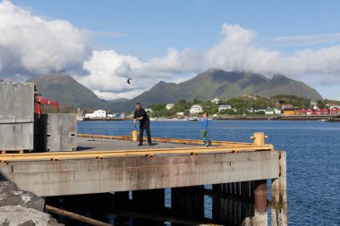Baba ve oğul gün batımında okyanusta sörf yapıyor. Şanslı balıkçılık.