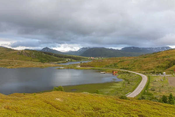 アスファルトの道路はノルウェーの極北の青いフィヨルドと苔の山の間を蛇行しています 選択的焦点 — ストック写真