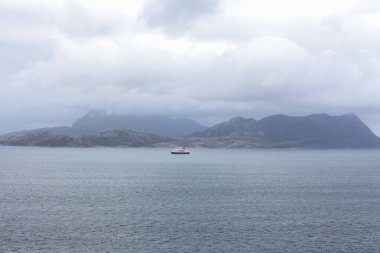 Norveç fiyortları ve dağları bulutlarla çevrili, gece yarısı güneşi, kutup günü, temiz suda fiyort yansıması. seçici odak.
