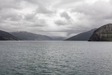 Norveç fiyortları ve dağları bulutlarla çevrili, gece yarısı güneşi, kutup günü, temiz suda fiyort yansıması. seçici odak.