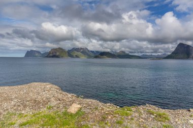 Norveç fiyortları ve dağları bulutlarla çevrili, gece yarısı güneşi, kutup günü, temiz suda fiyort yansıması. seçici odak.