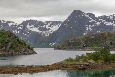 Norveç fiyortlarının manzarası. Yeşil tepeler, karlı tepeler