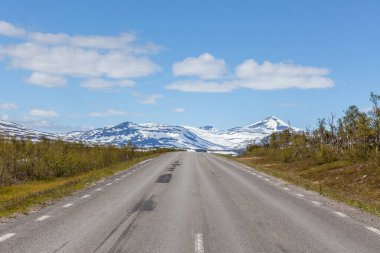 İsveç 'teki dağların arasındaki bir vadide geçen yol seçici bir odak noktası, İsveç dağları Norveç sınırında. kar zirveleri