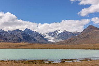 İnanılmaz Altai doğal manzarası, zümrüt sularıyla sakin göl, kasvetli, bulutlu gökyüzü ile çevrili inanılmaz dağ buzulları. Rusya, Çin ve Moğolistan sınırı