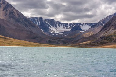 İnanılmaz Altai doğal manzarası, zümrüt sularıyla sakin göl, kasvetli, bulutlu gökyüzü ile çevrili inanılmaz dağ buzulları. Rusya, Çin ve Moğolistan sınırı