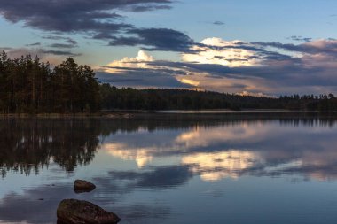 Gölün üzerinde gün batımı. Göl gün batımında bulutları yansıtır. İsveç