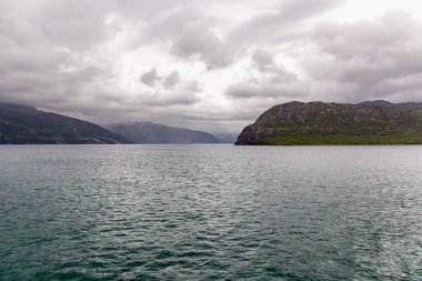 Norveç 'te gizemli bir fiyort. Dağlar ve sis, suyun üzerinde tek renkli güzel bir renkle süzülüyor. seçici odak