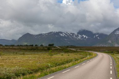 bulutlu gökyüzünün altında Norveç dağları arasında düz ve yalnız yol, seçici odaklanma