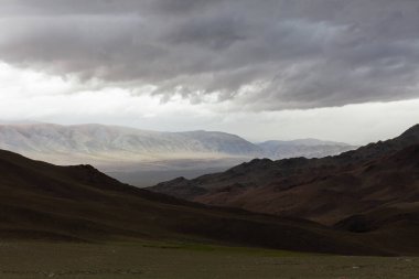Fırtınadan önce karanlık gökyüzünün altındaki Moğol dağları. Altai, Moğolistan