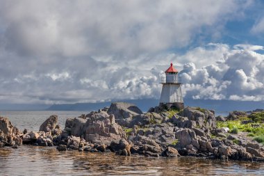 Norveç 'te beyaz deniz feneri. Uzun beyaz bir deniz feneri olan Norveç manzarası. Sert İskandinav doğasının arka planındaki deniz feneri. Norveç.