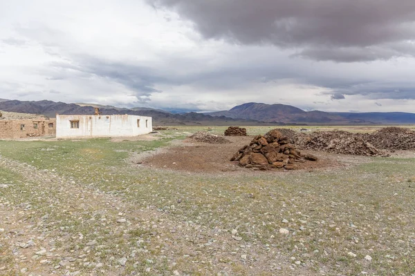 Winter dwelling and corral of nomadic people in the steppes of Mongolia. Pile of neatly complex dried manure in the foreground