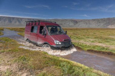 4WD arabası nehirde yürüyor. SUV arabasıyla nehir yolculuğu. Moğolistan - Altai. Fotoğraf içeriden çekilmiş.