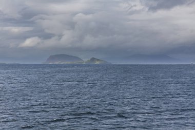 Norveç fiyortlarının bulutlu gökyüzü ve seçici odak noktalarıyla çevrili turkuaz su manzarası