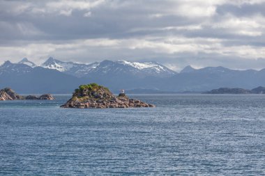 Norveç fiyortları ve dağları bulutlarla çevrili, gece yarısı güneşi, kutup günü, temiz suda fiyort yansıması. seçici odak.