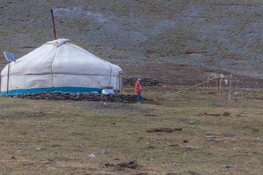 Altai, Moğolistan - 14 Haziran 2017: Moğolistan göçebelerinin küçük bir yerleşim yeri. Yurdun yanındaki kız turistlere bakıyor..