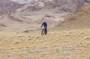 Altai, Moğolistan - 14 Haziran 2017: Moğolistan bozkırlarında motosiklet süren kasklı motosikletli gezgin.