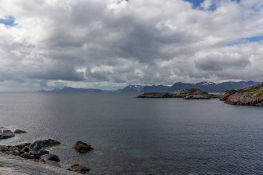Norveç fiyortları ve dağları bulutlarla çevrili, gece yarısı güneşi, kutup günü, temiz suda fiyort yansıması. seçici odak.